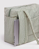 Ein silberner Laptop gleitet teilweise aus einer BAGGU Small Cloud Carry-On Tasche aus recyceltem Nylon mit grünen und weißen Streifen. Die Tasche hat einen Reißverschluss, zwei Tragegriffe und eignet sich als Flugzeug-Handgepäck.