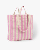 Die Stofftasche von OMOM by Main Design aus Bio-Baumwolle mit vertikalen rosa und beigen Streifen, zwei kurzen Griffen und einem langen Schulterriemen steht aufrecht vor einem schlichten weißen Hintergrund.