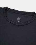 Eine Nahaufnahme des dunklen Rundhalsausschnitts des Aina Kinder UV Shirts von Main Design zeigt den Kragen, die Brust mit einem kleinen Logo, den UPF 50+ Schutz und die Größe "7/8", die in den Halsausschnitt gedruckt ist.