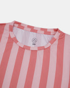 Eine Nahaufnahme des Main Design Aina Kinder UV Shirts mit vertikalen rosa und hellrosa Streifen. Es hat einen runden, gerippten Halsausschnitt, ein sichtbares "5/6"-Größenetikett und ist aus nachhaltigem Stoff mit UPF 50+ Schutz auf weißem Hintergrund gefertigt.