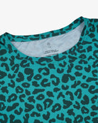 Nahaufnahme des Lush UV Surf Shirts von Main Design in blaugrünem und schwarzem Leopardenmuster mit HEIQ-Stoffkragen und LSF 50+ Schutz. Das Pflegeetikett mit Waschanleitung ist deutlich sichtbar.