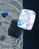 Zwei Haargummis und ein „Aloha Small Pouch“ aus der Aloha Collection schwimmen in einem Pool, während sich das Sonnenlicht auf dem Wasser spiegelt und verspielte Schatten wirft. Dieser stilvolle, wasserfeste „Aloha Small Pouch“ von Aloha Collection hält deine wichtigsten Utensilien trocken und verleiht jedem Badetag einen Hauch von pastellfarbenem Charme.