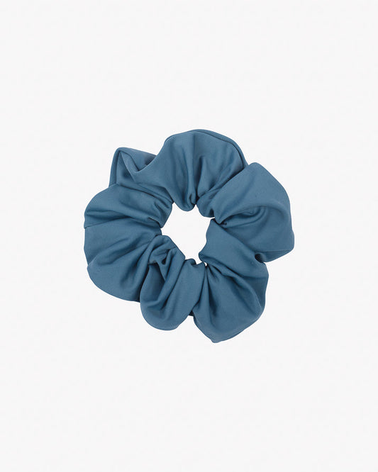 Ein blaugrünes Stoff-Scrunchie aus Stoffresten wird vor einem schlichten weißen Hintergrund präsentiert. Das Haargummi einfarbig von Main Design wirkt bauschig und ist kreisförmig angeordnet, was es zu einem stylischen und nachhaltigen Accessoire macht.