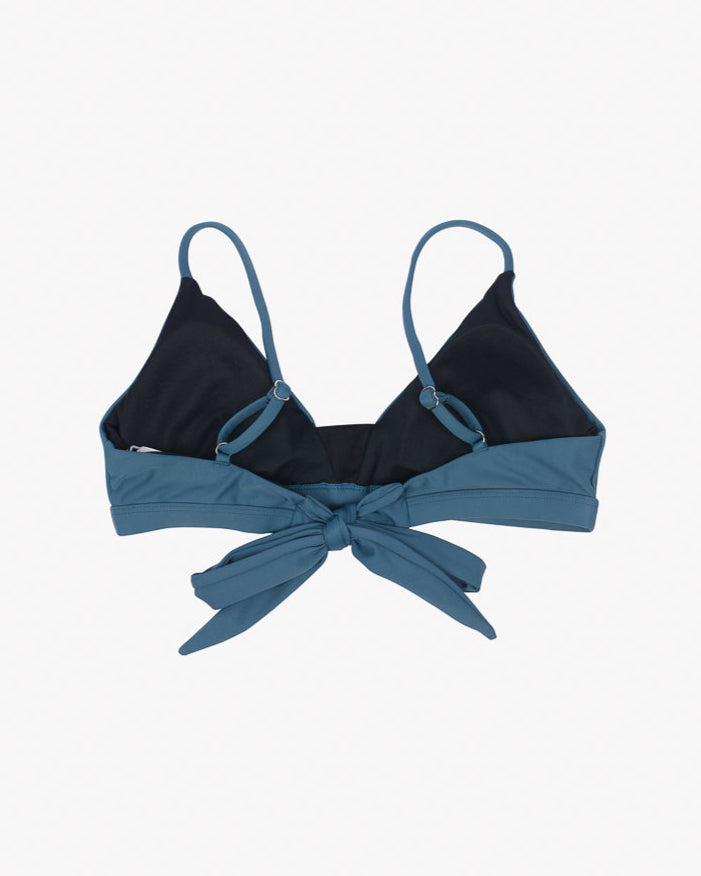 A blue Adore Triangel Bikini Oberteil from Main Design with thin, verstellbare Schulterträger and a front tie detail. The bikini features a dark, lined inside for added coverage. Made from umweltfreundlicher Stoff, the overall design is simple and stylish.