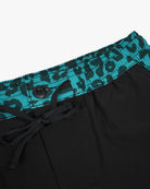 Die Nolan Boardshorts für Jungen von Main Design bestehen aus schwarzem Stretch mit elastischem Bund, türkisfarbenem Stoff, abstraktem schwarzem Muster und einem schwarzen Knopf. Hergestellt aus UPF 50+ Sonnenschutz 4-Wege-Stretch-Material für Komfort und Schutz.
