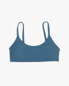 Das Sassy Bikini-Top von Main Design ist ein blaues Bralette mit zwei dünnen Trägern aus recycelten Materialien. Sein glatter, taillierter Stoff bietet einen nahtlosen Schnitt für ultimativen Komfort und ein schlichtes Design, das zu lässiger Kleidung passt. Der schlichte weiße Hintergrund unterstreicht seine lebendige Farbe und Form.