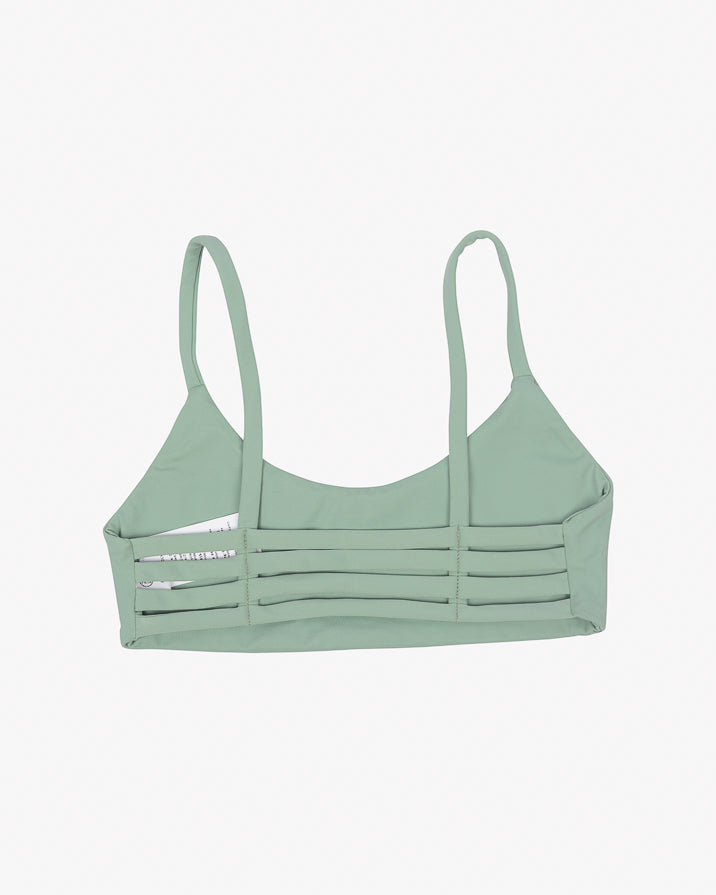 Das Sassy Bikini-Top von Main Design ist ein hellgrüner Sport-BH aus recycelten Materialien mit horizontalen, ausgeschnittenen Trägern auf der Rückseite, die sich vor einem schlichten weißen Hintergrund abheben.