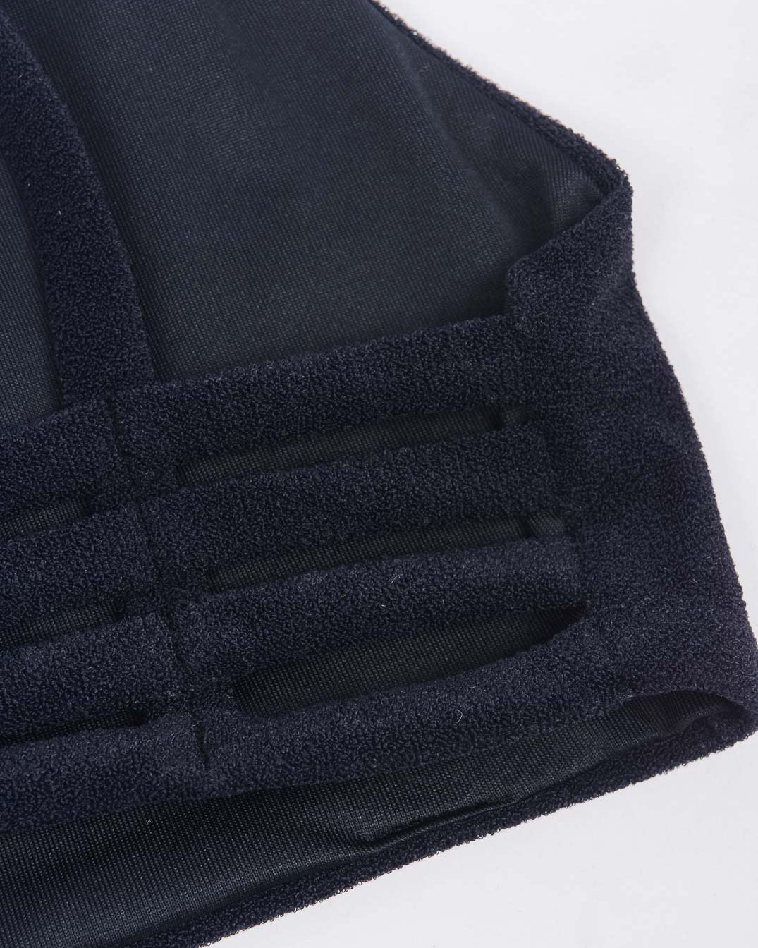 Nahaufnahme eines schwarzen Stoffes mit Netzüberzug und dicken Trägern in Gittermuster vom Sassy Bikini-Top von Main Design. Es wurde aus recycelten Materialien für strukturierte Elastizität gefertigt und bietet eine nahtlose Passform, die sich ideal für Sportbekleidung oder als Teil des Bikini-Oberteils eignet.