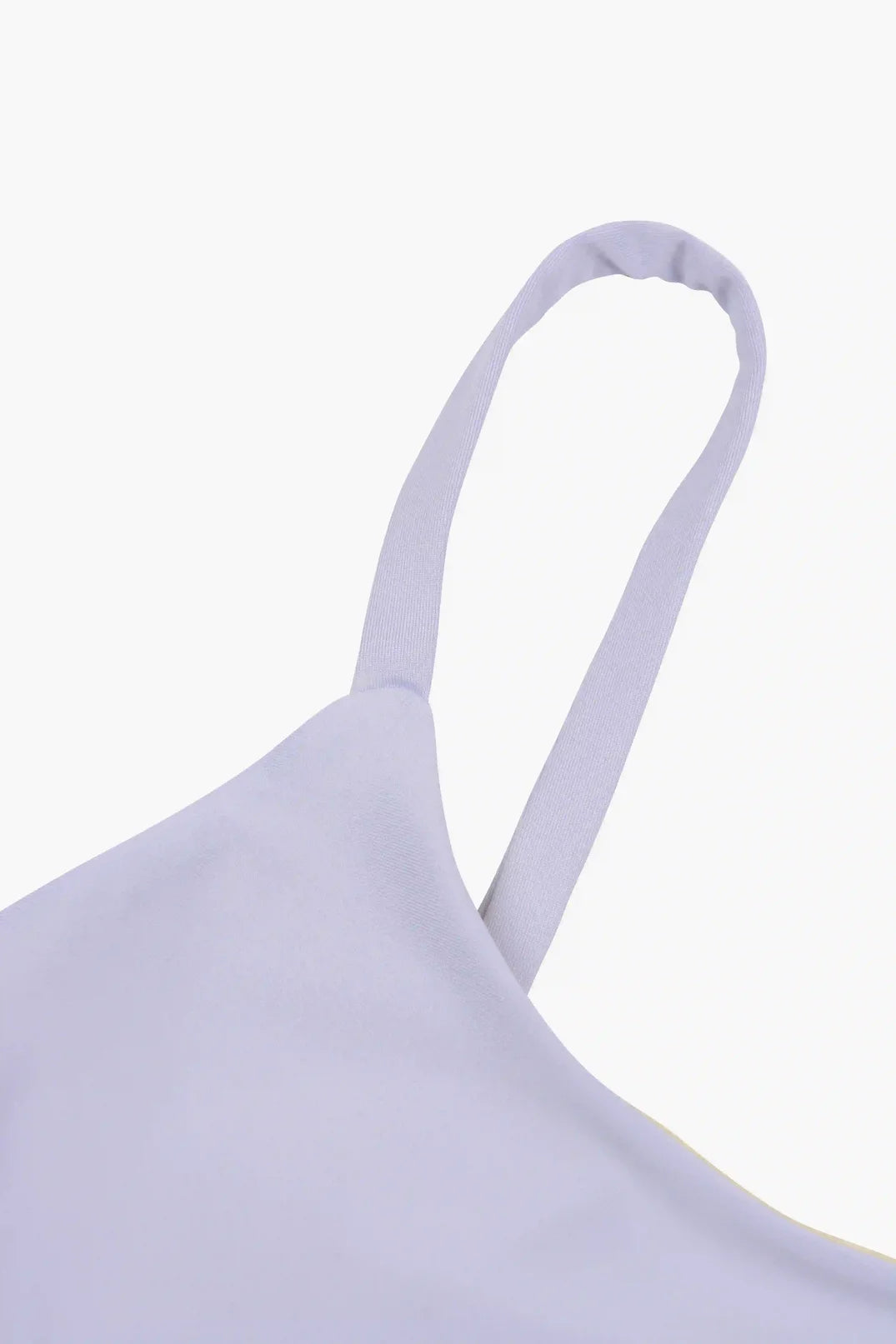 Nahaufnahme eines hellvioletten Spaghettiträgers auf dem Sassy Bikini Oberteil reversibel von Main Design vor einem weißen Hintergrund. Der Stoff wirkt glatt und leicht reflektierend und erinnert an das glatte Material, das in sportlichem Design verwendet wird.