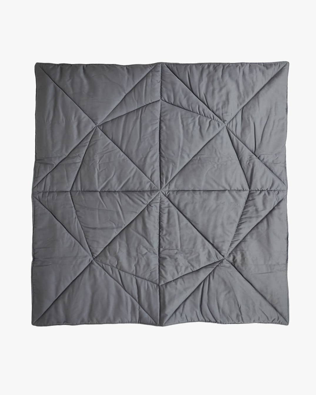 Ein Produkt von Main Design, die Spielmatte und Krabbeldecke Boot, ist eine bezaubernde handgefertigte Steppdecke, die durchgehend geometrische, dreieckige Muster aufweist. Das Design der Steppdecke ist in verschiedenen Grautönen gefertigt und erzeugt durch Stofffalten und Schatten ein strukturiertes Erscheinungsbild. Es wird schön auf einem hellen Hintergrund dargestellt.