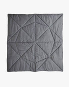 Ein Produkt von Main Design, die Spielmatte und Krabbeldecke Boot, ist eine bezaubernde handgefertigte Steppdecke, die durchgehend geometrische, dreieckige Muster aufweist. Das Design der Steppdecke ist in verschiedenen Grautönen gefertigt und erzeugt durch Stofffalten und Schatten ein strukturiertes Erscheinungsbild. Es wird schön auf einem hellen Hintergrund dargestellt.