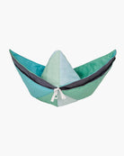 Ein handgefertigtes Spielzeug von Main Design, die „Spielmatte und Krabbeldecke Boot“, hat ein plüschiges, mehrfarbiges Design in Form eines Papierboots mit verschiedenen Blau- und Grüntönen und ist vorne mit einer weißen Schleife verziert.