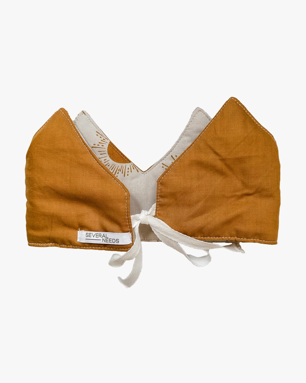 Eine wendbare braun-weiße Stoffkrone von Several Needs by Main Design, handgefertigt in Bali mit spitzen Kanten, weißem Futter, Bindeverschluss vorne und "SEVERAL NEEDS"-Anhänger. Ideal als Krone für Kinder.