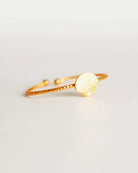 Der Ring von Adorabili ist ein zarter Goldring mit strukturierter Ringschiene und kleinem Muschel-Anhänger, handgefertigt in Frankreich von der Marke Adorabili, präsentiert auf weißem Hintergrund.