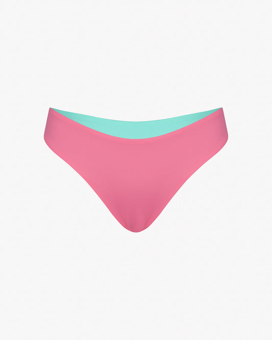 Die Luxe Bikini Hose von Main Design besteht aus einem Bikinihöschen im brasilianischen Schnitt in Pink mit einem aquamarinblauen Innenbund aus recycelten Materialien auf schlichtem weißem Hintergrund.