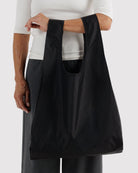BAGGU Standard Tragetasche in Black: Schwarze Tragetasche an der Hand getragen.