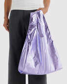 BAGGU Standard Tragetasche in Lavender Metallic: Lavendelfarbene Metallic-Tragetasche an der Hand getragen.